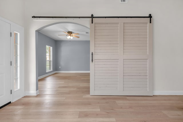 entrance foyer featuring light hardwood / wood-style flooring, a barn door, and ceiling fan