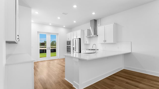 kitchen with white cabinetry, french doors, wall chimney range hood, stainless steel appliances, and light hardwood / wood-style floors