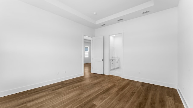 empty room with hardwood / wood-style flooring and a tray ceiling