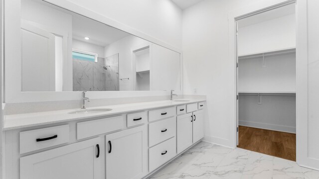 bathroom featuring tiled shower, dual vanity, and tile patterned floors