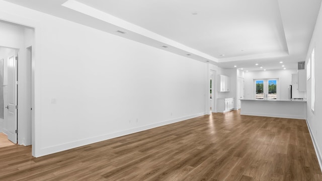 unfurnished living room with a tray ceiling and hardwood / wood-style flooring