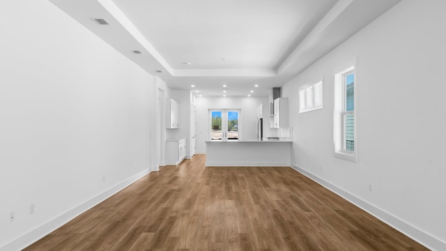 unfurnished living room with a tray ceiling and light hardwood / wood-style flooring