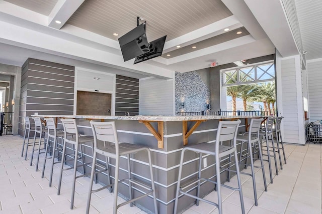 kitchen featuring beam ceiling, a kitchen breakfast bar, light tile patterned floors, and wooden ceiling