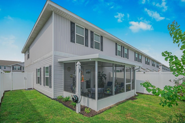 back of house with a sunroom and a lawn