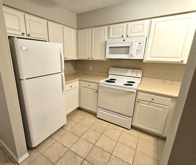 kitchen with light tile patterned floors, white appliances, white cabinetry, and a textured ceiling