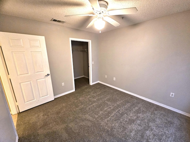 unfurnished bedroom featuring ceiling fan, a textured ceiling, a closet, and dark colored carpet