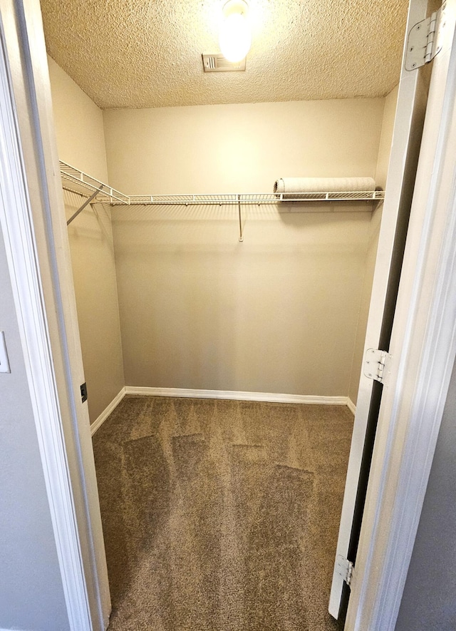 walk in closet with dark colored carpet