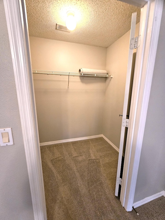 walk in closet featuring dark carpet