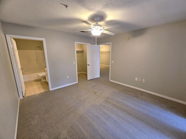 unfurnished bedroom with light carpet, ceiling fan, a closet, and ensuite bath