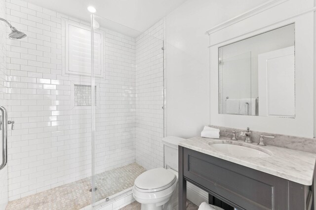 bathroom featuring vanity, walk in shower, and toilet