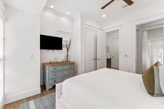 bedroom featuring hardwood / wood-style flooring, a closet, ceiling fan, and crown molding