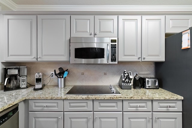 kitchen featuring tasteful backsplash, white cabinets, light stone counters, and black appliances