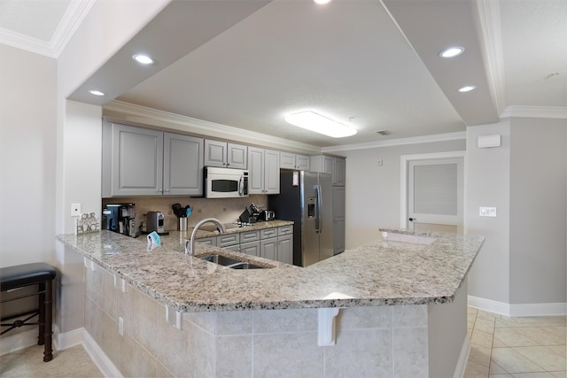 kitchen with sink, gray cabinets, stainless steel appliances, a kitchen bar, and kitchen peninsula