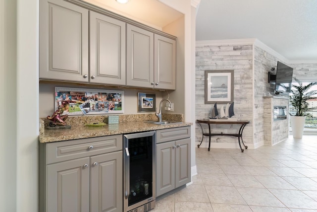 bar with sink, light tile patterned floors, crown molding, wine cooler, and light stone countertops