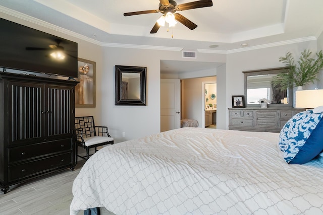 bedroom with ceiling fan, ornamental molding, a raised ceiling, and light hardwood / wood-style flooring