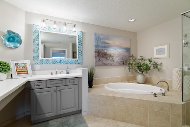 bathroom with tiled tub, vanity, tile patterned flooring, and a textured ceiling