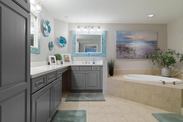 bathroom with tile patterned flooring, vanity, and tiled tub