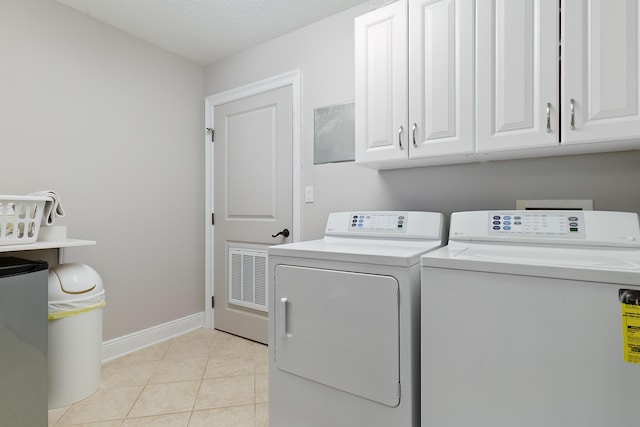 laundry room featuring cabinets, light tile patterned flooring, and independent washer and dryer