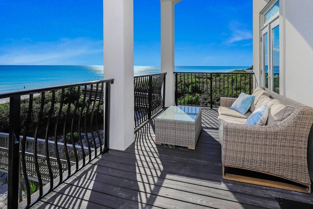 balcony with a water view, an outdoor living space, and a view of the beach