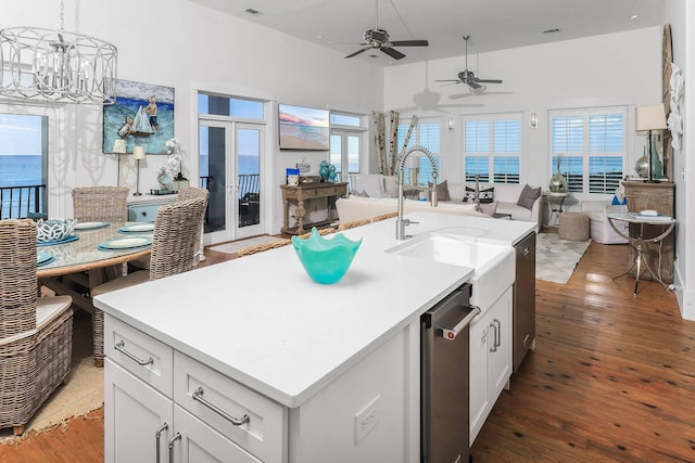 kitchen featuring sink, a kitchen island with sink, a water view, wood-type flooring, and white cabinets