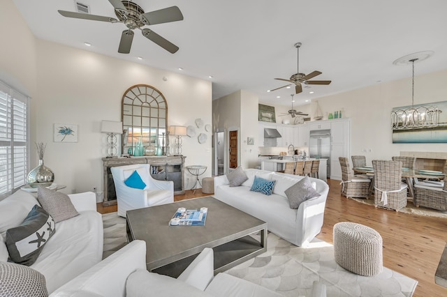 living room with ceiling fan with notable chandelier and light hardwood / wood-style flooring