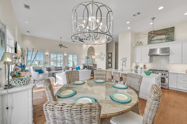 dining space featuring sink, ceiling fan with notable chandelier, and light hardwood / wood-style flooring