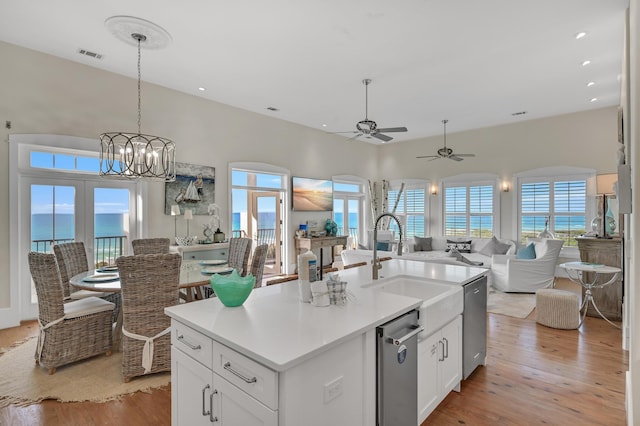 kitchen with a water view, a kitchen island with sink, white cabinets, and light hardwood / wood-style flooring