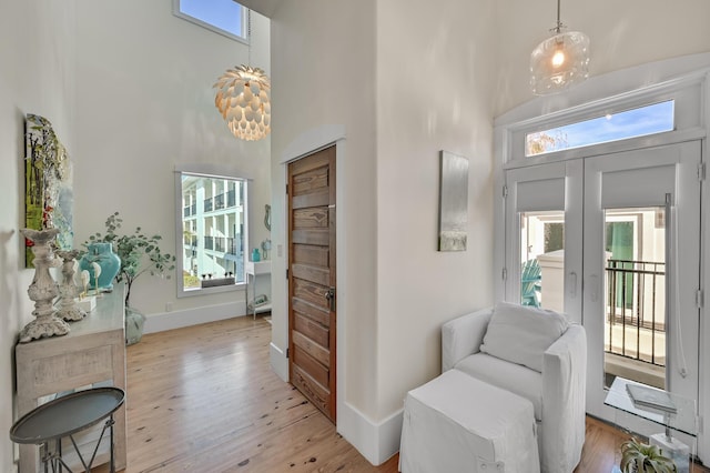 entrance foyer featuring a towering ceiling, light hardwood / wood-style flooring, and french doors