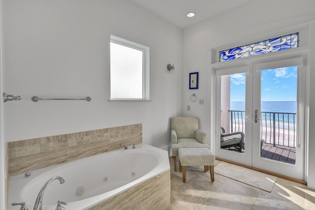 bathroom with a view of the beach, a water view, tile patterned floors, and french doors