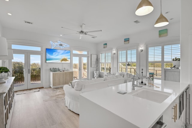 kitchen featuring french doors, decorative light fixtures, sink, and light hardwood / wood-style flooring