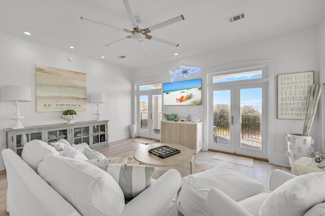 living room with french doors, ceiling fan, and light wood-type flooring