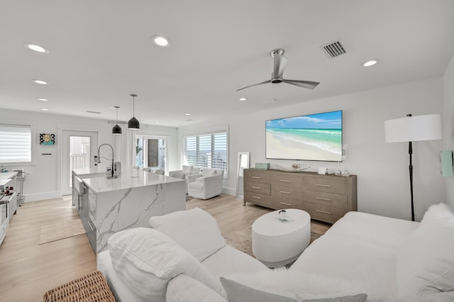 living room with ceiling fan and light hardwood / wood-style flooring