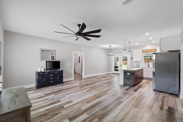 kitchen with french doors, stainless steel refrigerator, a kitchen island, pendant lighting, and white cabinets