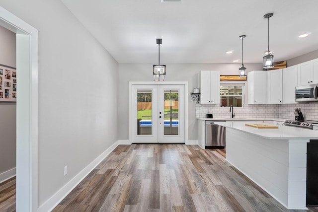 kitchen featuring stainless steel appliances, white cabinetry, pendant lighting, and french doors