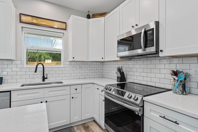 kitchen featuring tasteful backsplash, appliances with stainless steel finishes, sink, and white cabinets