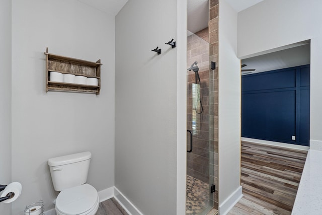 bathroom featuring toilet, a shower with shower door, and hardwood / wood-style floors