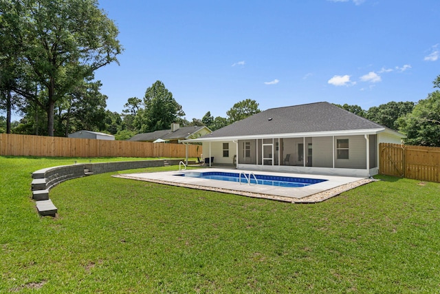 rear view of property featuring a fenced in pool, a patio area, a sunroom, and a lawn