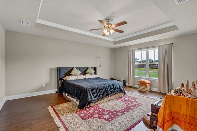 bedroom featuring wood-type flooring, ceiling fan, crown molding, and a tray ceiling