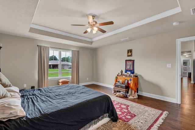 bedroom with ornamental molding, dark hardwood / wood-style flooring, ceiling fan, and a raised ceiling