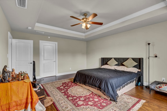 bedroom featuring ceiling fan, wood-type flooring, ornamental molding, and a tray ceiling