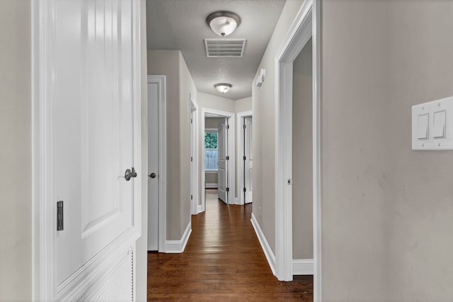 hallway with dark hardwood / wood-style floors and a textured ceiling