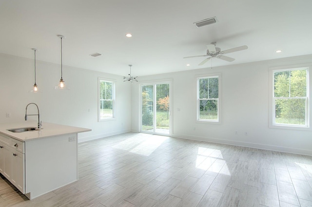 kitchen featuring pendant lighting, white cabinetry, sink, a kitchen island with sink, and a healthy amount of sunlight