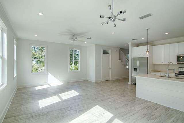 kitchen featuring sink, crown molding, white cabinetry, hanging light fixtures, and stainless steel appliances