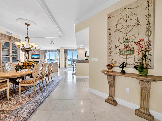 tiled dining space featuring crown molding and a chandelier