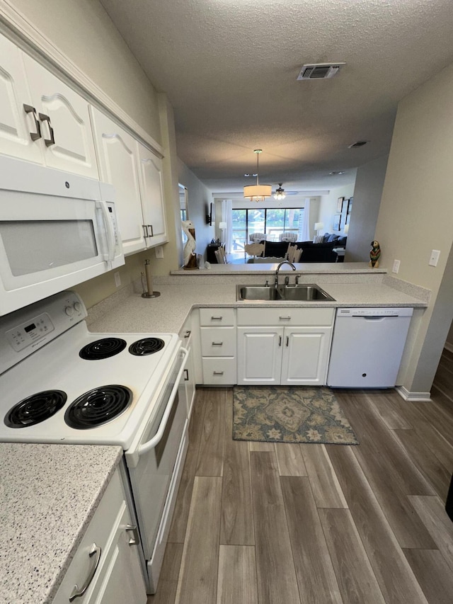 kitchen with sink, white appliances, white cabinetry, a textured ceiling, and kitchen peninsula