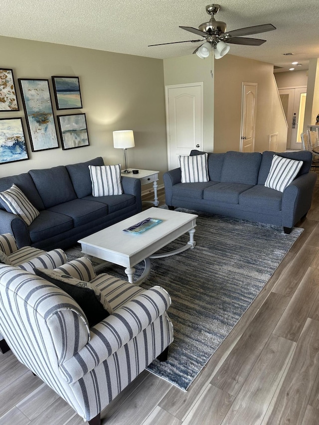 living room featuring ceiling fan and a textured ceiling