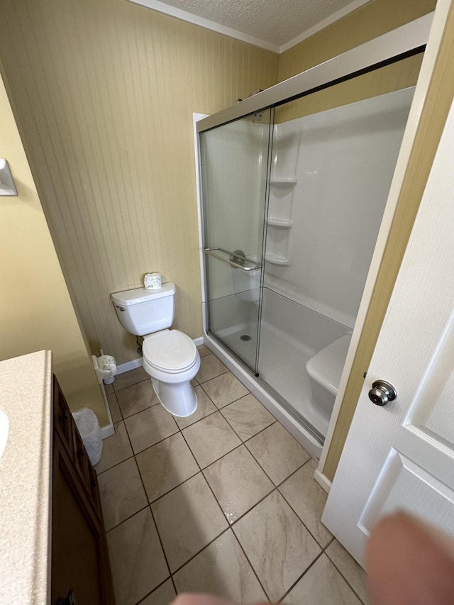 bathroom featuring walk in shower, vanity, toilet, and tile patterned flooring