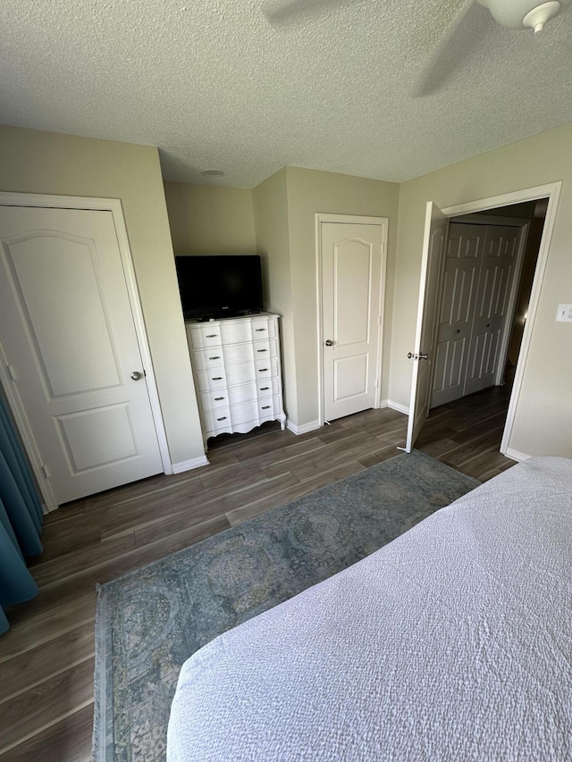 bedroom with a textured ceiling, dark hardwood / wood-style floors, and ceiling fan