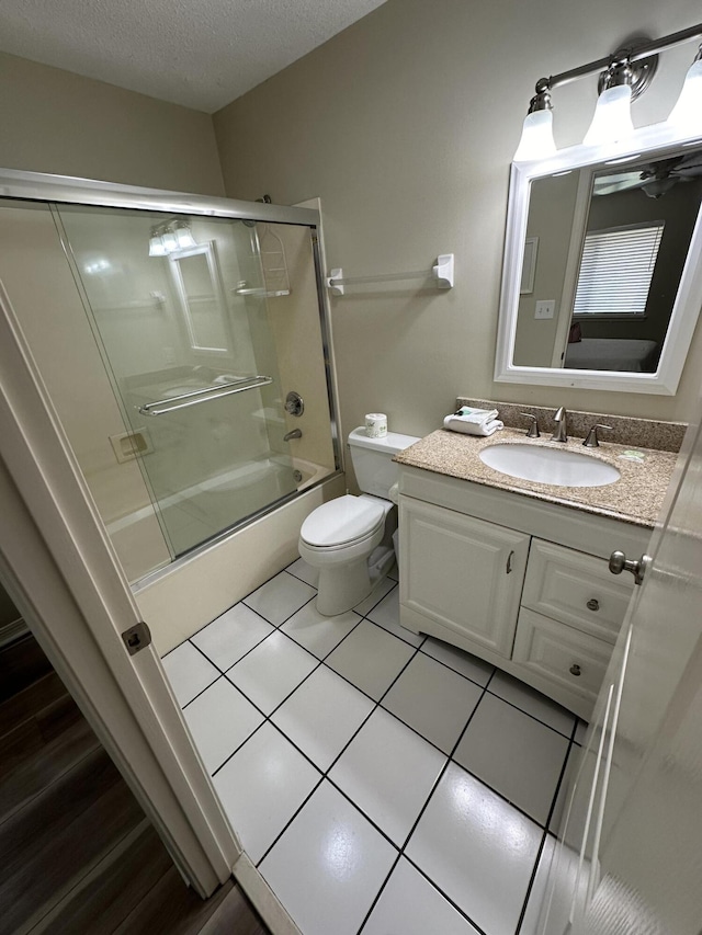 full bathroom with enclosed tub / shower combo, vanity, a textured ceiling, tile patterned floors, and toilet