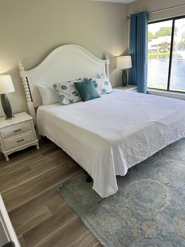 bedroom featuring a water view and dark wood-type flooring